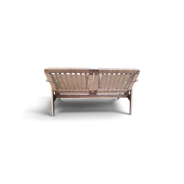This Hans Wegner style loveseat was likely made in the 1950s by an unknown producer in Yugoslavia. It features natural...