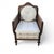 French provincial style cane armchair with a carved wood frame, woven cane panels, cream striped upholstery, and round...