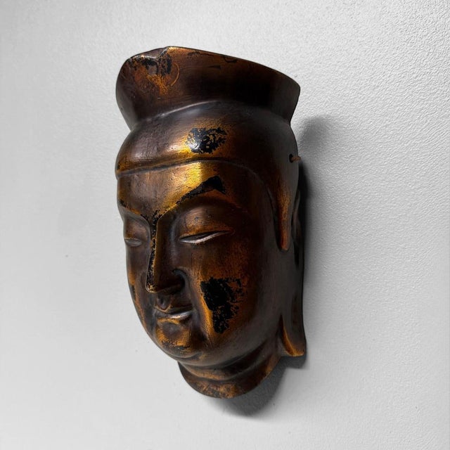 A refined Japanese decorative mask of Miroku Bosatsu, with a dark golden-brown finish, serene expression and deep, time-...