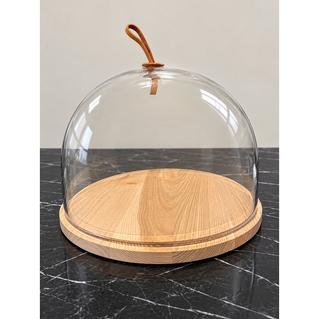 The Ivalo dome by LSA International, the London glassware studio: a mouth-blown glass cloche on a solid ash base with a...