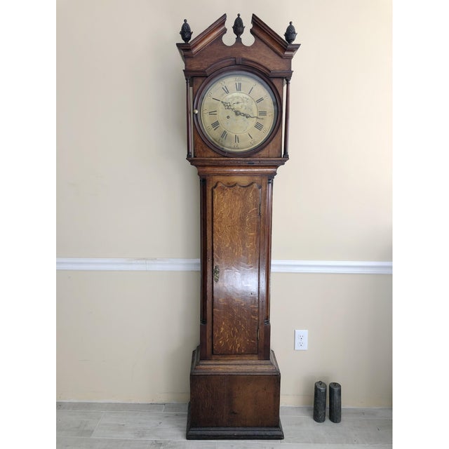 An antique oak tall case clock (or grandfather clock) with a natural highly figured wood with great patina, a distinctive...
