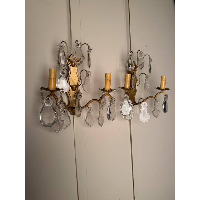 Pair of two-arm French wall sconces dating to circa 1890, crafted in bronze and crystal with elegant decorative detailing....