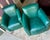 Green leather club chairs with a curved Art Deco silhouette. Each chair has a deep seat cushion, flared backrest, and dark...