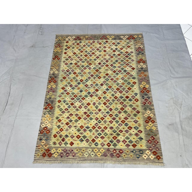 This Afghan Chobi wool kilim features a soft mint green field with an all-over tribal geometric floral pattern in rust...