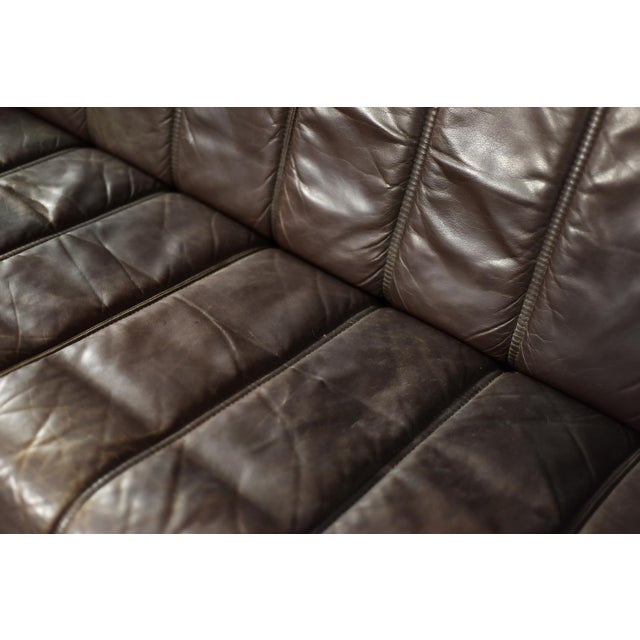 This three-seater sofa was manufactured in Denmark during the 1970s. The frame is crafted from solid wood in a honey-brown...