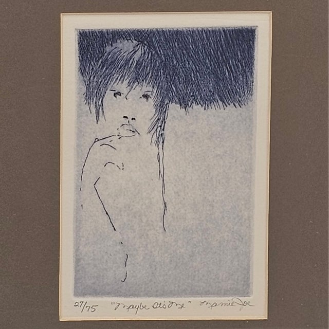 There’s a question in her eyes, lingering like the last word in a love letter never sent. Inked in moody blue, etched with...