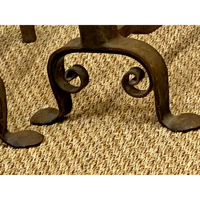 This pair of andirons feature hand forged iron work and vintage brass with a beautiful patina.