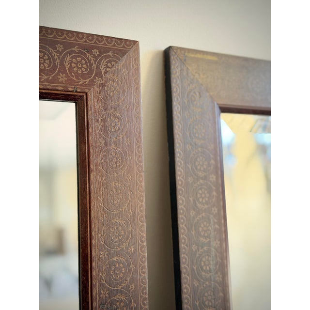 Striking pair of vintage solid wood mirrors featuring hand-painted parcel-gilt decoration over a rich reddish-brown...
