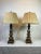 Pair of wooden candlestick style lamp featuring an aged gold finish, square footed base and 20" silk pleated shade with...