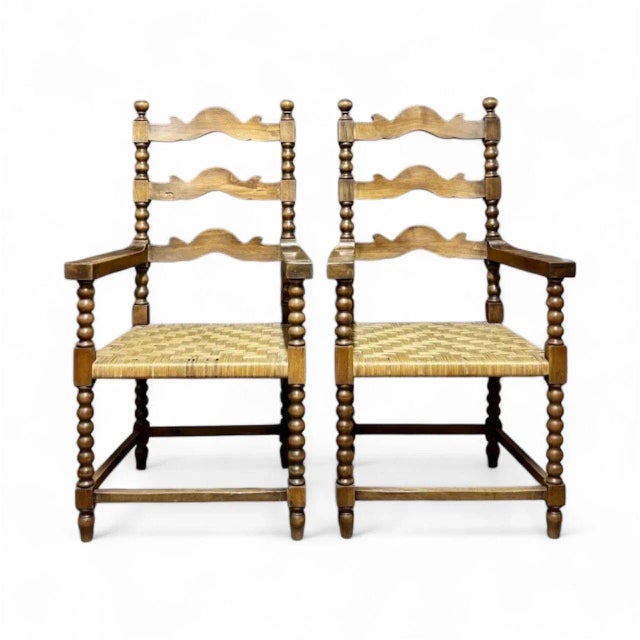 Spanish rustic armchairs circa 1850, in the Jacobean style, made of stained oak, with flat wicker on the seat and ladder-...