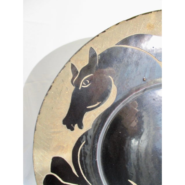 Large charger in terra cotta with incised rampant horse over whole face. Glossy black glaze with bisque negative space....