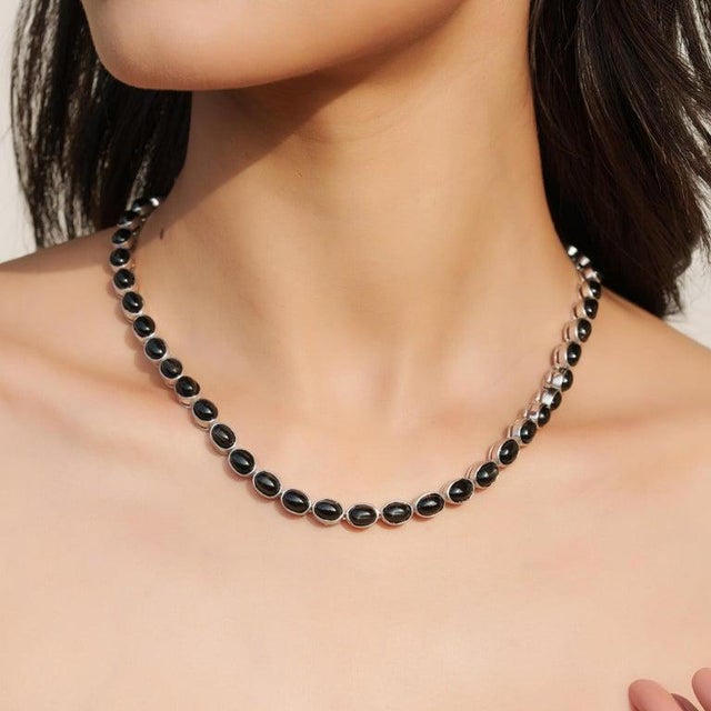 This bold and sophisticated tennis necklace is expertly crafted in 925 sterling silver and set with natural black star...