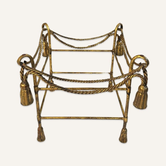 Pair of gilt metal Hollywood Regency glass top side tables with rope and tassel decoration from the 1940s. These tables...