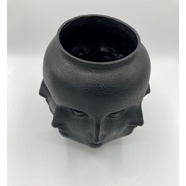 This is a black vase with multiple faces (of a woman I think) by TMS branded as 'Vitruvian man' after da Vinci's famous...