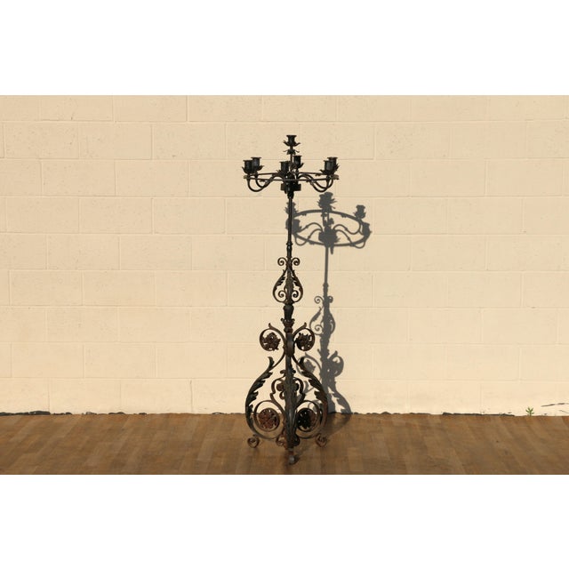 Striking early 20th-century wrought iron floor candelabra featuring seven candle holders and an elaborate hand-forged...