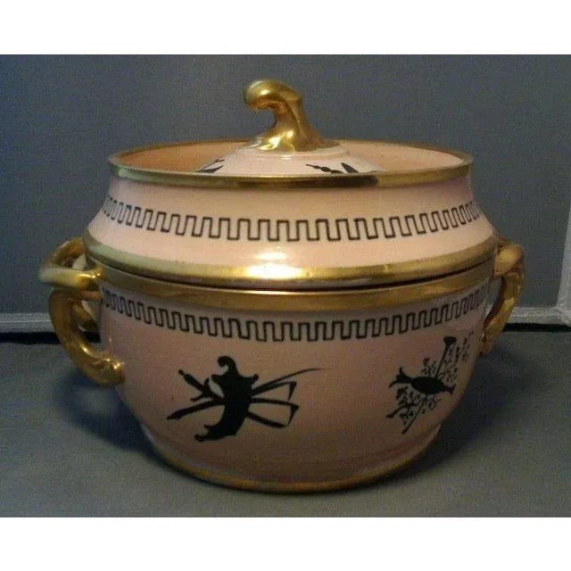 A lovely and rare Coalport fruit cooler having pink salmon ground and gilt highlights. Decorated with black trophies of...