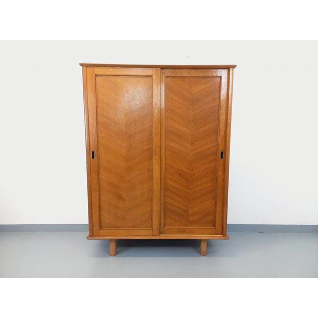 Vintage 1960s oak wardrobe with cylindrical legs and ample storage: two sliding doors with a large hanging rail and a...