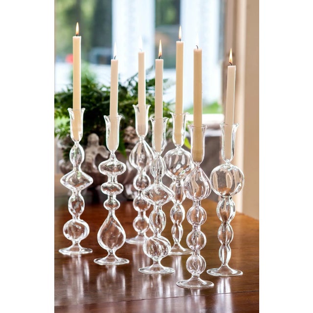 A grouping of four mouth-blown candlesticks in clear glass, each with a different design. Create your own distinctive...