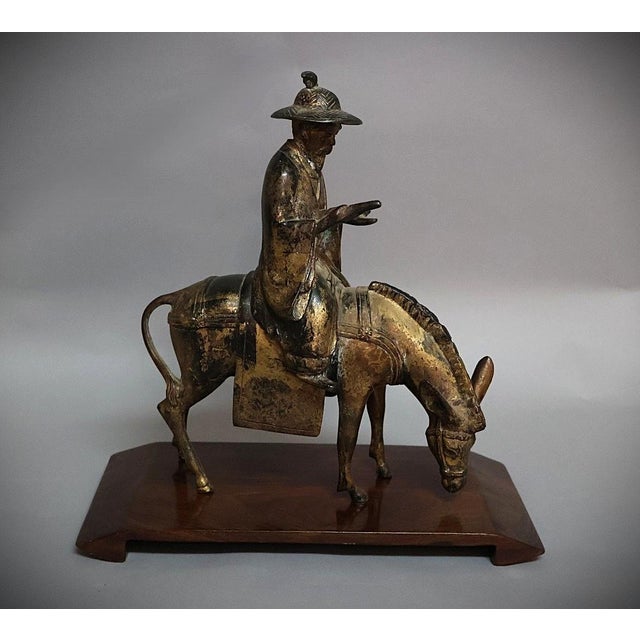 A finely cast Chinese bronze figure depicting Zhang Guolao, one of the Eight Immortals of Daoist tradition, seated upon a...