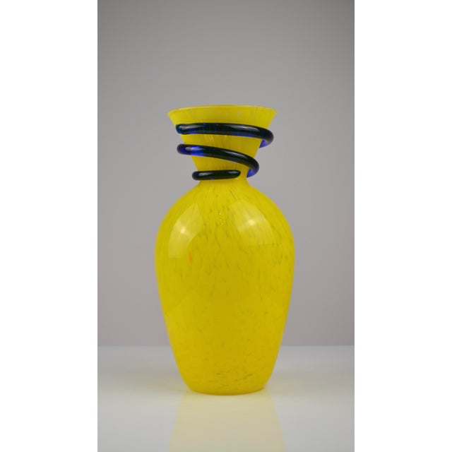 Striking sculptural art glass vase featuring a vibrant yellow body with subtle internal streaking and a dramatic cobalt...