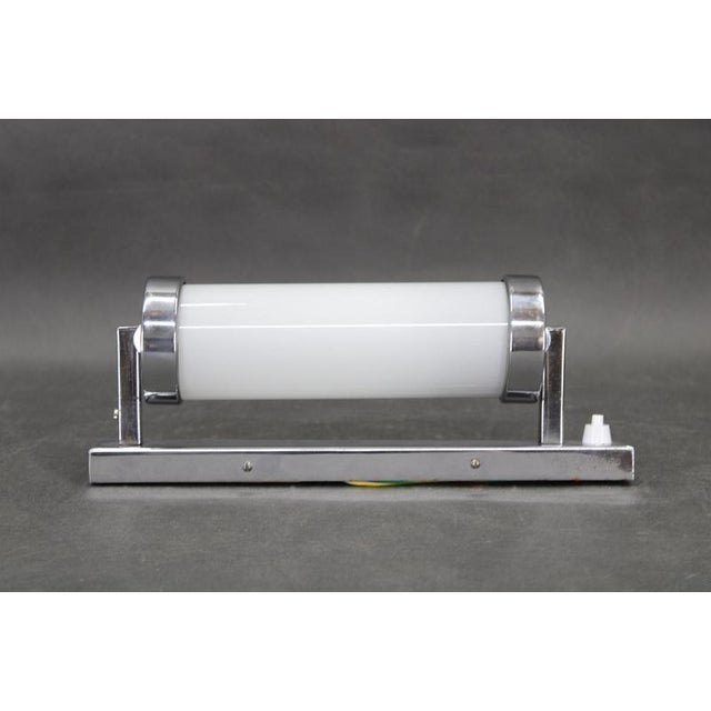 A rare bauhaus tubular wall light from 1930s czechoslovakia, combining a milky cylindrical glass shade with chrome-plated...