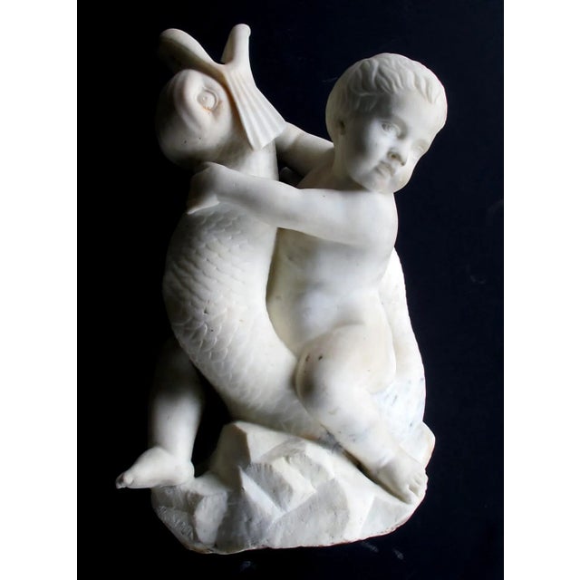 An expressive and well-carved Itallian Rococo Revival Carrara marble niche fountain of a putti seated on a dolphin; the...
