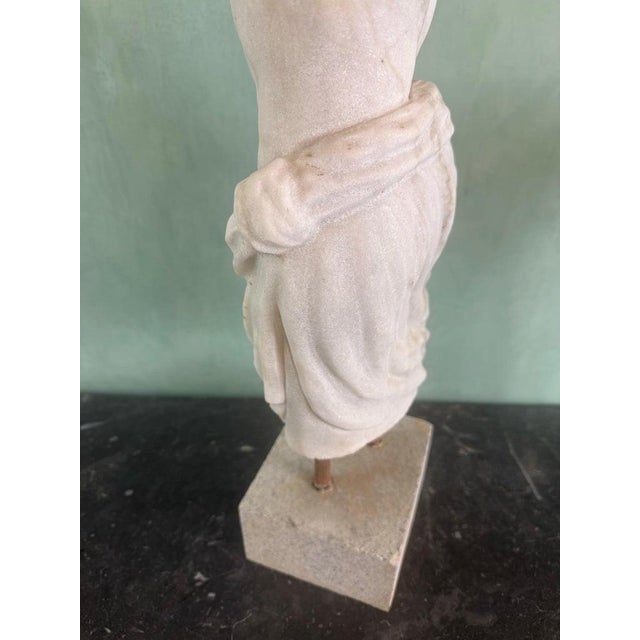 A compelling classical-style marble torso fragment, carved in the manner of Greco-Roman antiquity, depicting the athletic...