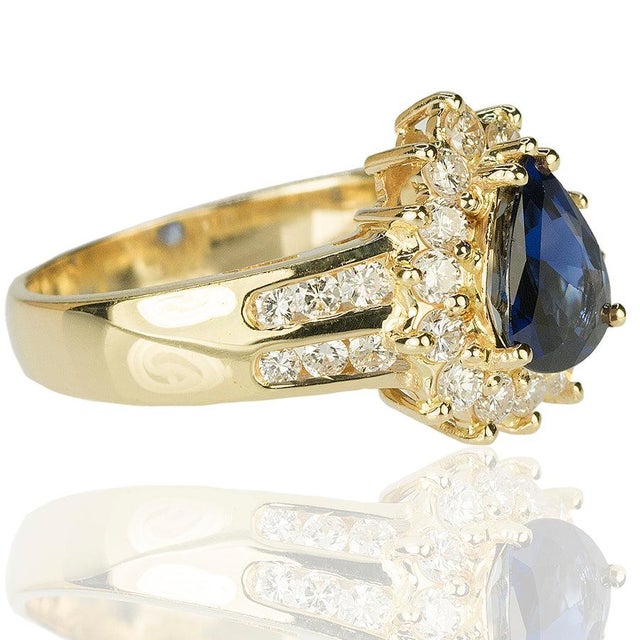 18kt Yellow Gold ring containing one pear shape sapphire weighing 1.55 carats and 26 round diamonds weighing 0.95 carats...