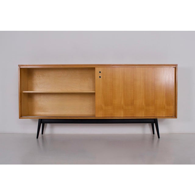 Modernist sideboard with sliding doors, anonymous edition from the 1950s. Doors in figured sycamore maple, black lacquered...