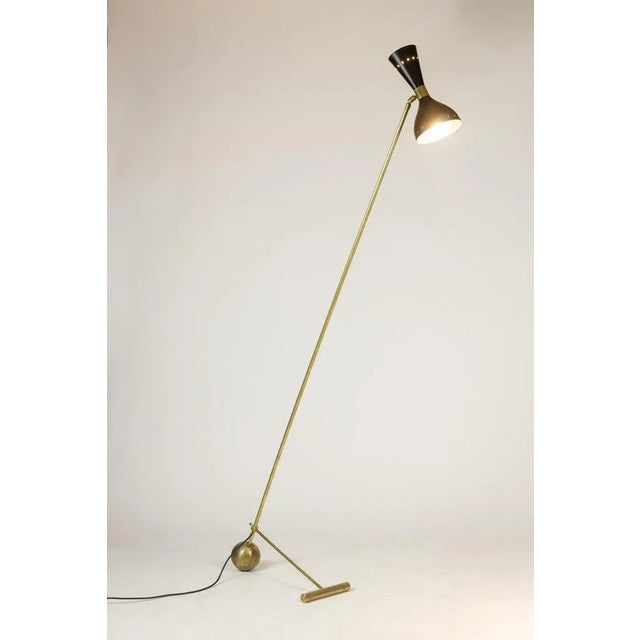 Two-light floor lamp in black perforated sheet metal and matt gold brass. Italian work realized in the 1960s. This piece...