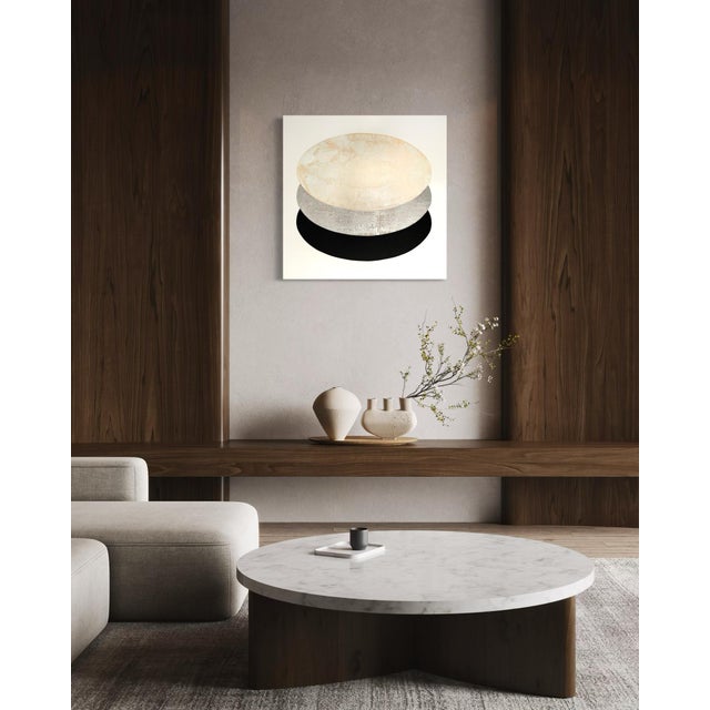 The pale ellipse form returns at full scale here, its surface a soft topography of brushed white shifting into silvered...