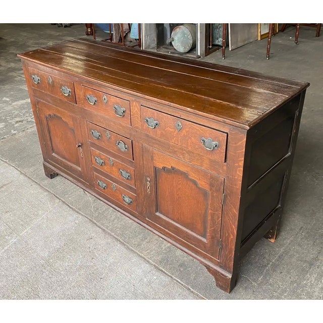 19th century Welsh oak dresser base. 3 drawers over 2 doors and 2 faux bottom drawers, paneled doors and bracket feet.