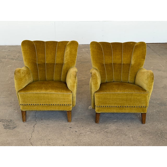 Scandinavian wingback lounge chairs from the 1940s, retaining their original olive-green velvet throughout. The channel-...