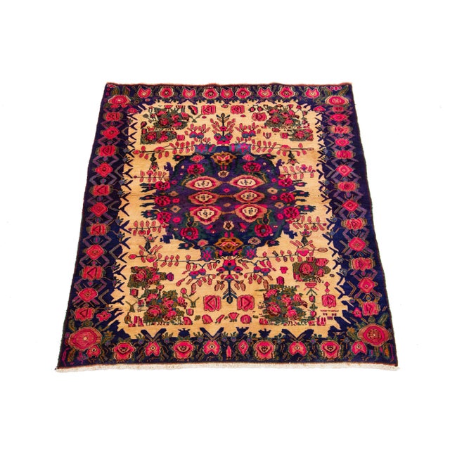 This vintage Bidjar hand-knotted wool rug has a blue and tan field with a rosette design in purple, pink, and green. This...