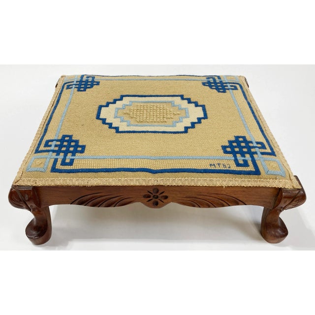 Vintage rectangular 4-legged carved wood footstool featuring needlepoint top with deep tan background textile and rich...