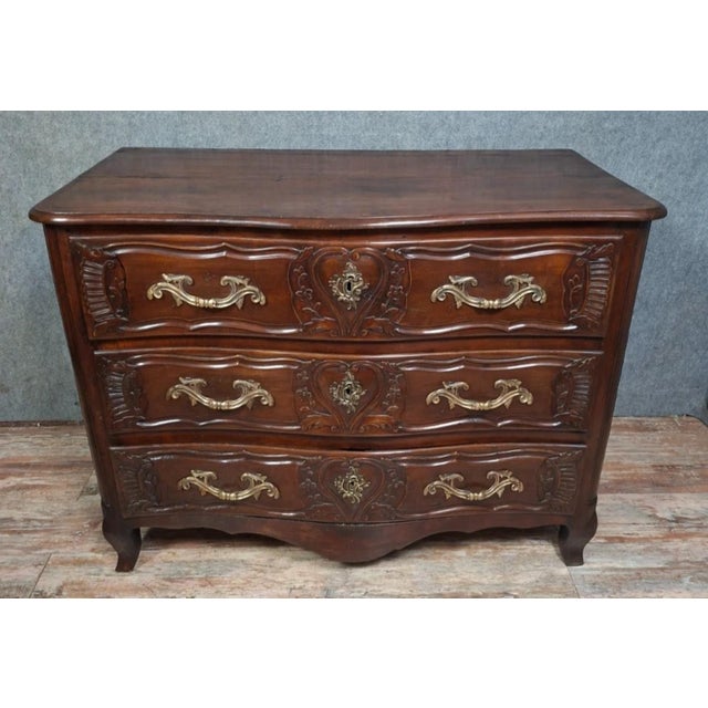 A louis xv/18th-century lyonnaise commode in molded and carved walnut, opening at the front with three wide drawers. it...