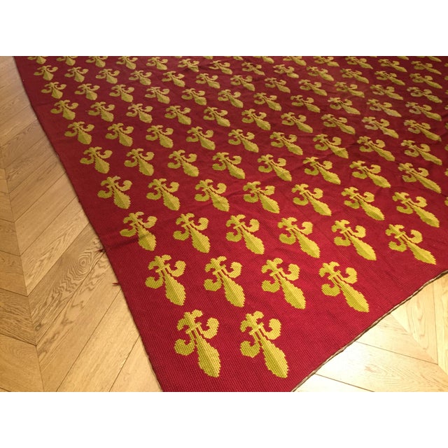 This large antique rug is embroidered in needlepoint with thick wool featuring the french lily in yellow and light green...