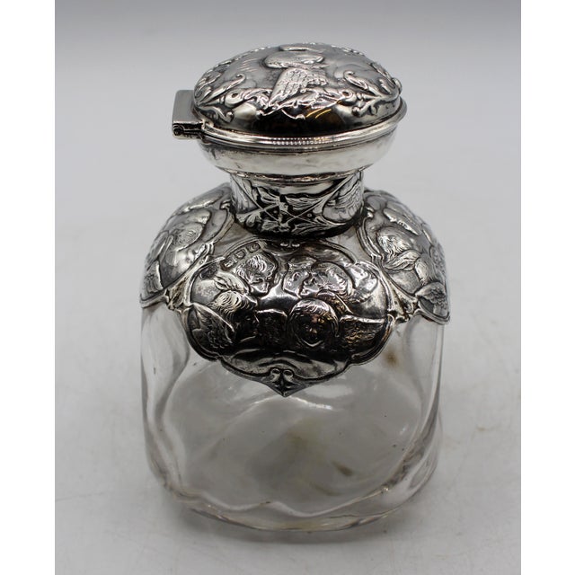 London, 1898, sterling and blown glass scent bottle. Pinched form. The silver decorated with large cartouches of little...