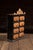 Painted tin spice cabinet featuring eight small drawers arranged in a two-column grid, each fitted with rounded copper-...
