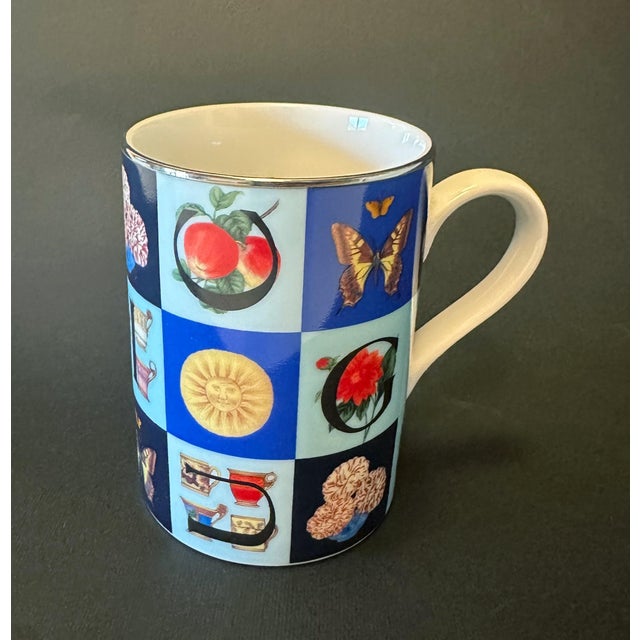 "Guccissimo" porcelain mug featuring bright polychrome design with a predominance of blue and large letters forming the...