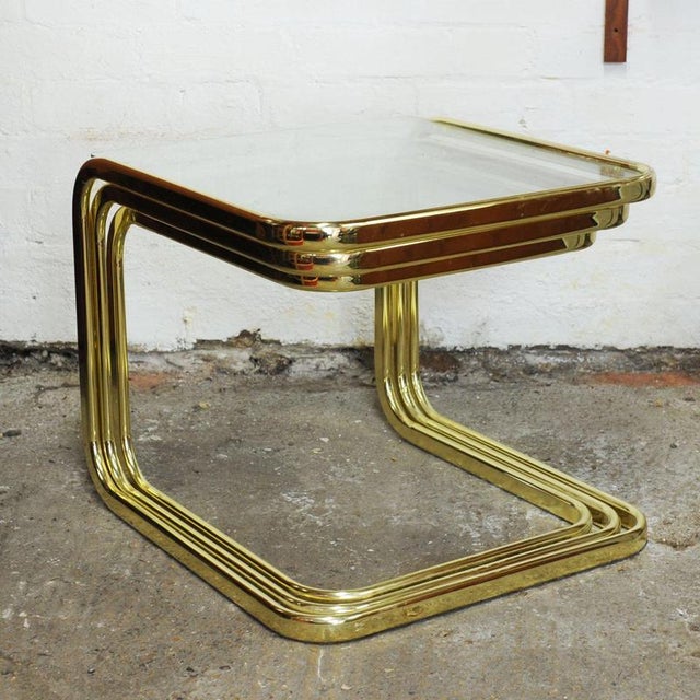 A vintage set of 3 table in smoked glass and brass nesting tables attributed to Milo Baughman. This piece is attributed to...