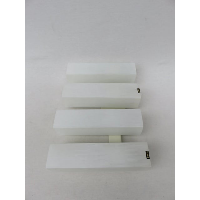 This set of 3 wall lights impress with their reduced, strict form. The glass cylinders are striped white and the wall...