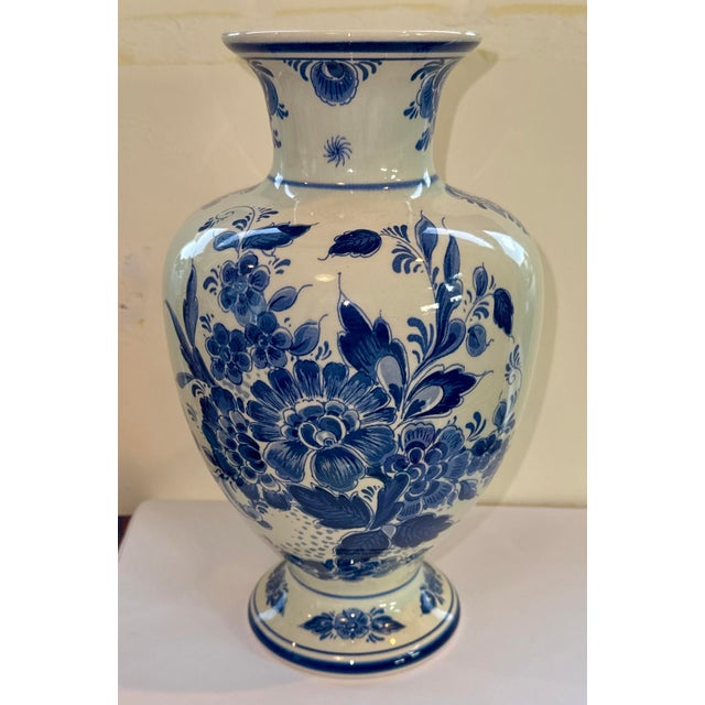 Mid-Century Hand-Painted Delft Vase This elegant Delft vase stands out with its rich cobalt floral motif, delicately hand-...