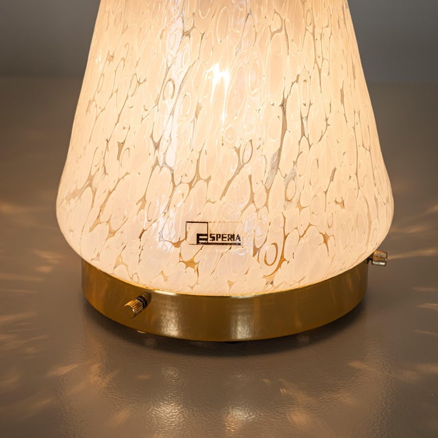 Set of two conical table lamps made of white speckled Murano glass with refined brass fittings. Each lamp bears the...