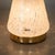 Set of two conical table lamps made of white speckled Murano glass with refined brass fittings. Each lamp bears the...