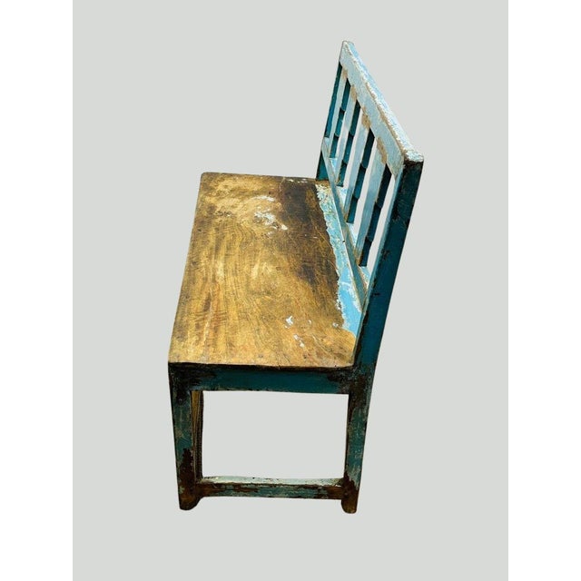 This rustic distressed wooden bench features a striking blue paint finish with an aged patina, adding vintage character to...