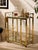 A glamorous vintage bar cart featuring a polished brass-tone metal frame with clean architectural lines and an open, airy...