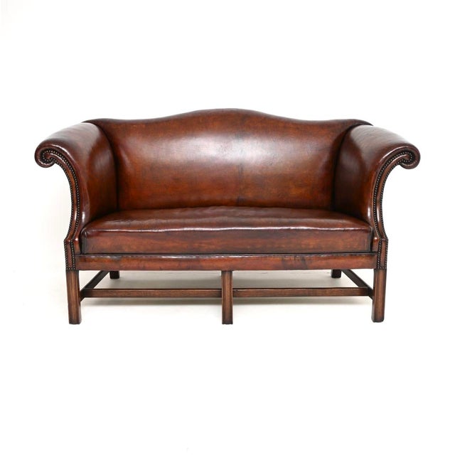 A stunning antique leather hump back sofa in the Chippendale style, made in England and likely dating from around the...