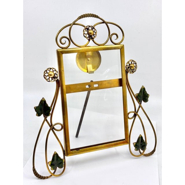 The picture frame is a whiplash design. An art deco style picture frame. The frame is made of brass and glass. The round...