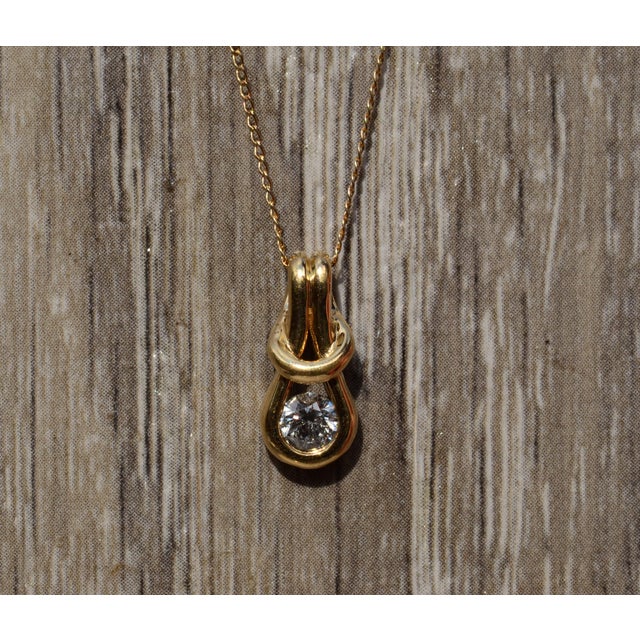 The Alderly Street: Yellow Gold Love Knot Diamond Solitaire Necklace. The necklace features a 0.36 carat round brilliant...